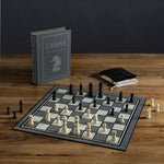 Chess Vintage Bookshelf Edition in play. Fabric-wrapped book with integrated storage. Full-sized folding game board, 32 Wooden Chess pieces, 2 Fabric pouches and instructions.