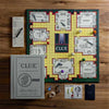 Clue board game in play. Clue Vintage Bookshelf Edition. A tribute to the classic 1949 game board and cards, wood movers with die-cast bases, die-cast weapons, pad of detective notes and 6 pencils.