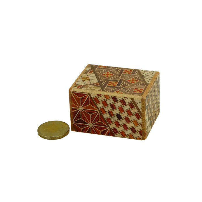 Japanese puzzle box shown with coin for size comparison.